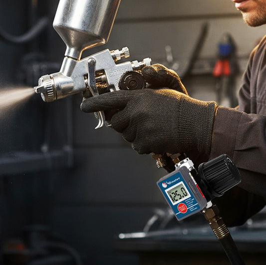 DAR02B digital air regulator mounted at the inlet of an HVLP spray gun as a technician sprays in a workshop