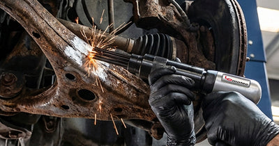 A technician using a Le Lematec air needle scaler to remove rust and scale from a heavy metal part.